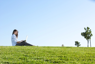 woman in a field, on a laptop